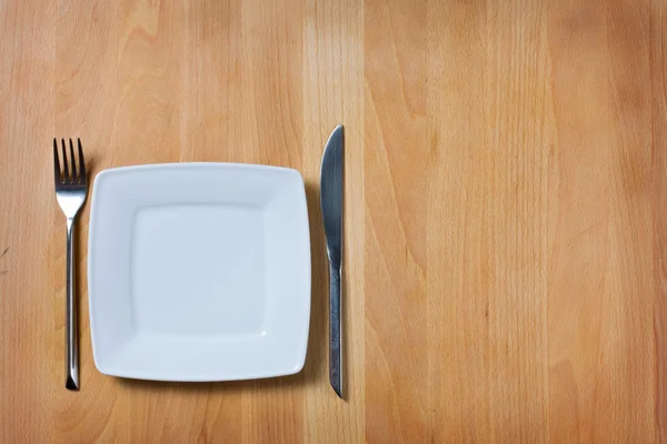 Assiette vide avec fourchette et couteau sur table en bois, disposition de la table — Photo