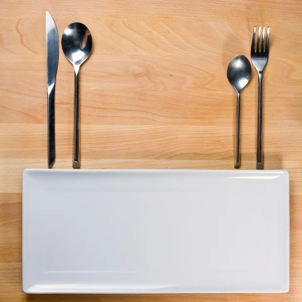 Assiette vide avec fourchette et couteau sur table en bois, disposition de la table — Photo