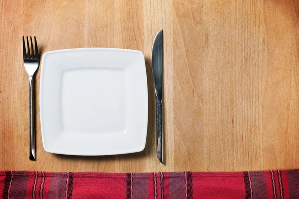 Empty plate with fork and knife on wooden table, table arrangement — Stock Photo, Image