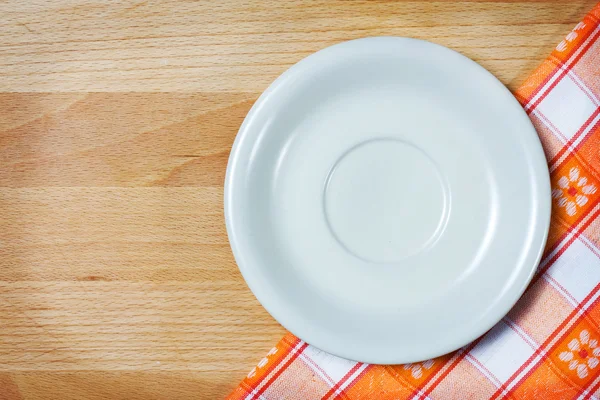 Empty plate on tablecloth over wooden background — Stock Photo, Image