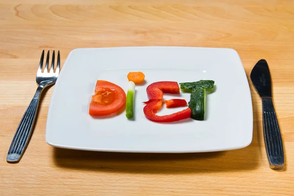 Placa com legumes e dieta palavra sobre fundo de madeira — Fotografia de Stock