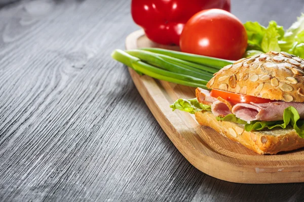 Um sanduíche fresco com presunto, rabanete, tomate — Fotografia de Stock