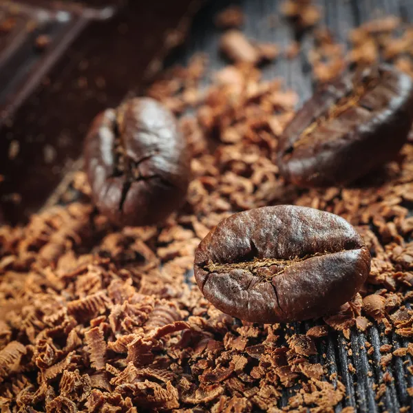 Frisch geröstete Kaffeebohnen und ein Stapel brauner Schokolade — Stockfoto