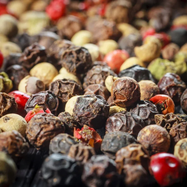 Pepper corns on a wooden board — Stock Photo, Image