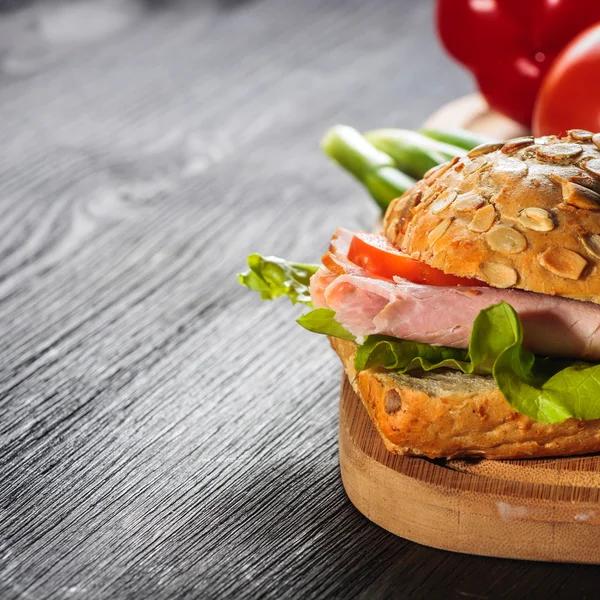 Ham sandwich with lettuce on wood background — Stock Photo, Image