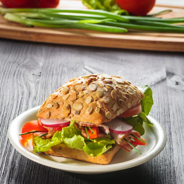 Broodje ham met sla op hout achtergrond — Stockfoto