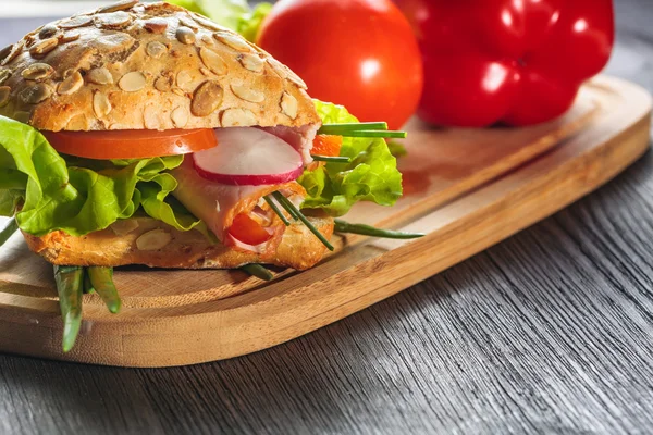 Broodje ham met sla op hout achtergrond — Stockfoto