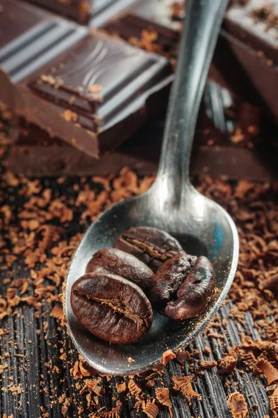 Chicchi di caffè su cucchiaio e cioccolato, primo piano — Foto Stock