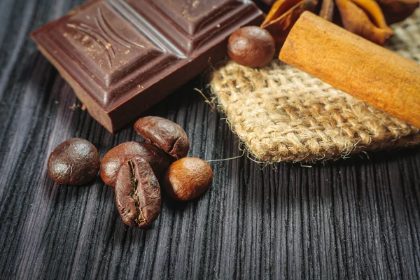 Chocolate bar and spices on wooden table — Stock Photo, Image