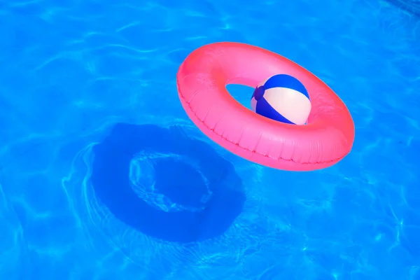 Colorful inflatable ball and round tube floating in swimming pool — Stock Photo, Image