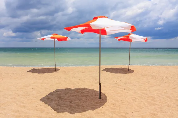 Bulutlu mavi gökyüzü ile sahilde plaj şemsiyeleri — Stok fotoğraf