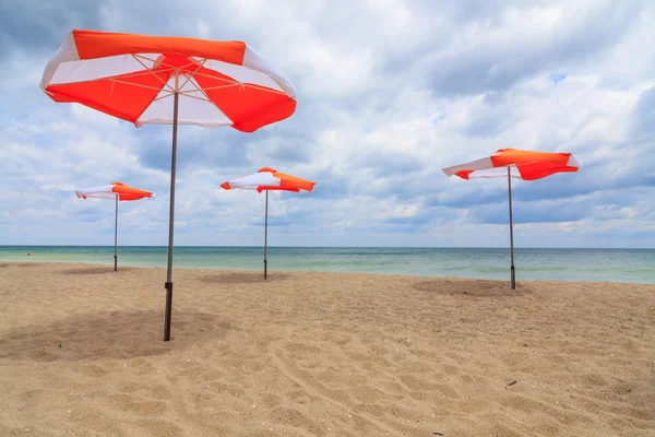 Guarda-chuvas de praia na praia com céu azul nublado — Fotografia de Stock