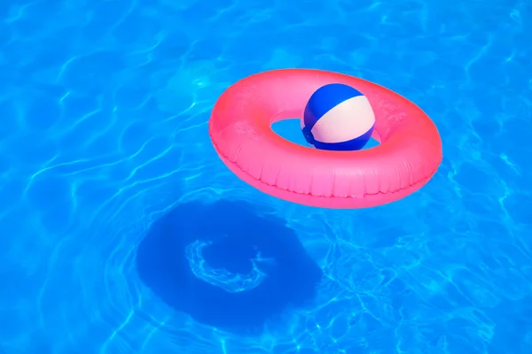Colorful inflatable ball and round tube floating in swimming poo — Stock Photo, Image