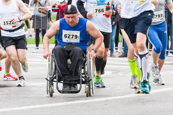 KRAKOW, POLONIA - 28 de mayo: Maratón de Cracovia. Hombre discapacitado no identificado en maratón en silla de ruedas en las calles de la ciudad el 18 de mayo de 2014 en Cracovia, POLONIA —  Fotos de Stock