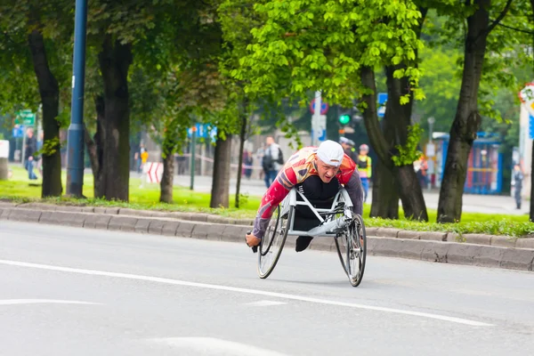 KRAKOW, POLONIA - 28 de mayo: Maratón de Cracovia. Hombre discapacitado no identificado en maratón en silla de ruedas en las calles de la ciudad el 18 de mayo de 2014 en Cracovia, POLONIA — Foto de Stock