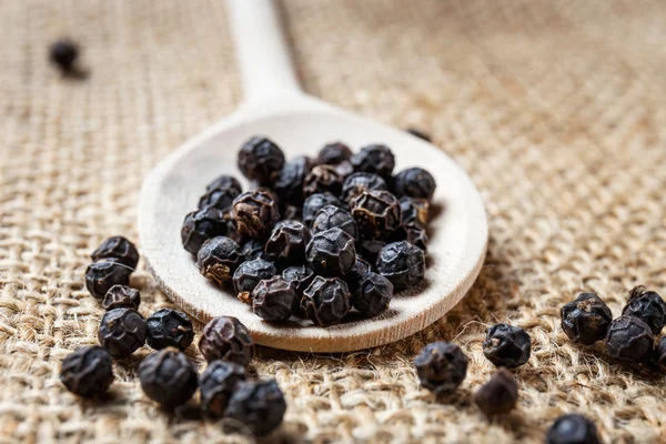 Black pepper on the wooden spoon — Stock Photo, Image