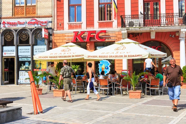 BRASOV, ROMANIA - JULY 15: Council Square on July 15, 2014 in Brasov, Romania. People buying fried chicken at local Kentucky Fried Chicken Restaurant. — Stock Photo, Image