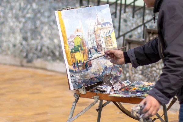 Ein älterer Künstler malt ein Ölgemälde. Pinsel in der Hand. Das ist nicht der Fall. — Stockfoto
