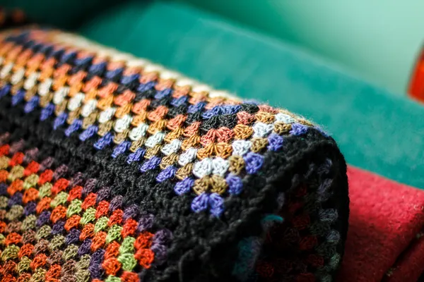Рулонна гачком ручної роботи афганська ковдра з бабусиних квадратів. Дощовик — стокове фото