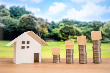 Beyaz bir model ev ve bozuk paranın tepesinde tahta bir küp..