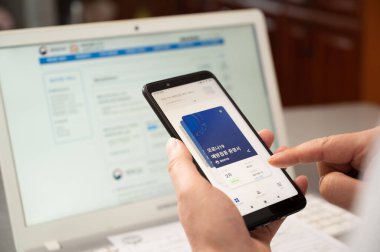 Seul, Güney Kore - Ekim 2021: Çevrimiçi COVID-19 aşı sertifikasını akıllı telefon uygulaması ile kontrol eden kişi