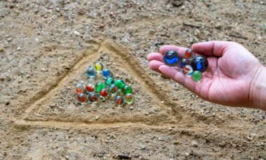 Oyun alanında çamurla misket oynayan bir adamın eli.