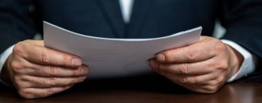 Elinde beyaz kağıt tutan bir işadamı..