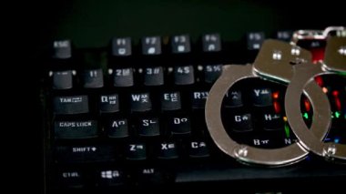 Klavye ve LED ışıkları açık kelepçeler. Siber suç kavramı.