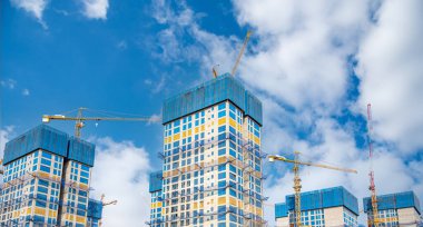 Gökyüzünde pek çok inşaat kulesi vinci olan bir panorama..