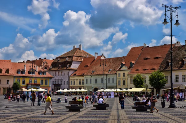 SIBIU, RUMANIA - 08 DE JUNIO DE 2014: Los turistas visitan la plaza principal en Sibiu, Rumania. Sibiu fue designada Capital Europea de la Cultura para el año 2007 — Foto de Stock