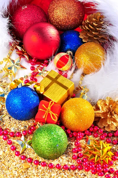 Christmas baubles and gift boxes in the christmas hat on the sand — Stock Photo, Image