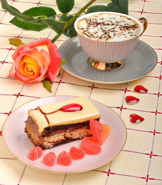 Cup of coffee, a rose and a cake on the tablecloth — Stock Photo, Image