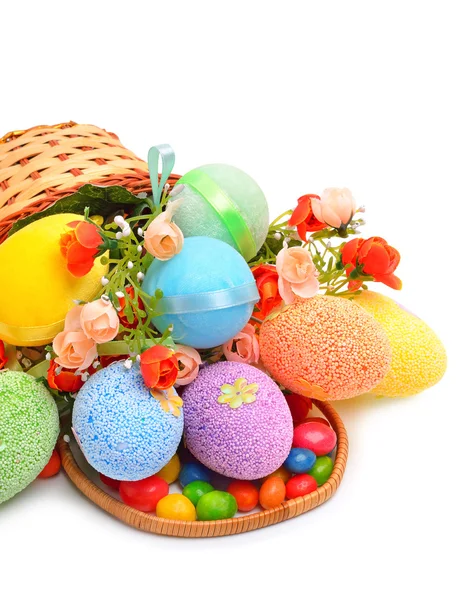 Easter colorido ovos de plástico, flores e caramelos na cesta — Fotografia de Stock