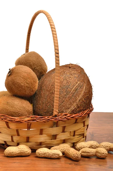Coconut, kiwi, peanut in the basket on the wooden board — Stock Photo, Image