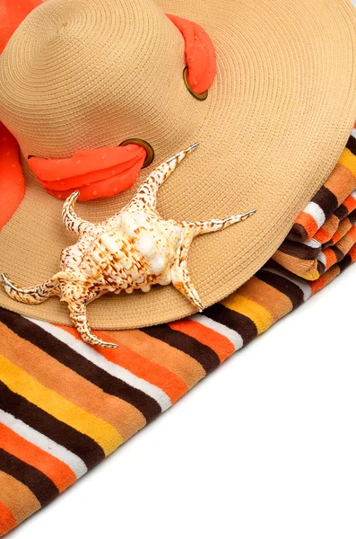 Woman beach hat, bright towel and a seashell — Stock Photo, Image