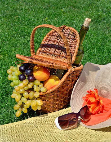 Sombrero de playa, gafas de sol, cesta de picnic con frutas y botella de —  Fotos de Stock