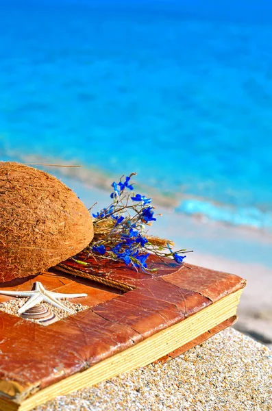 Vintage album on the sand with coconut shell and flowers — Stock Photo, Image