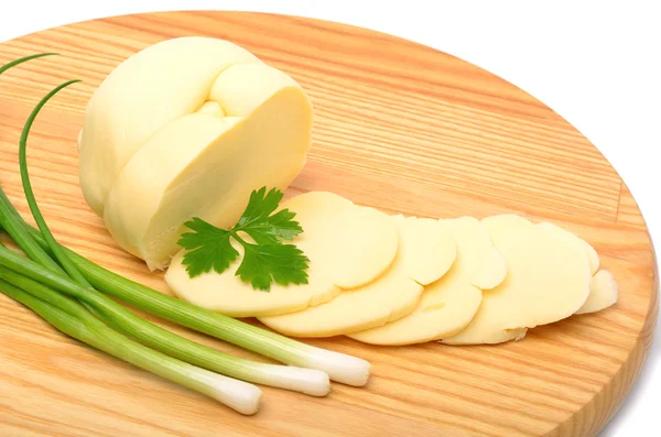 Sýr, plátky sýra a zelené cibule na dřevěné desce — Stock fotografie