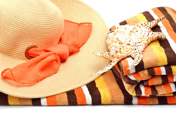 Woman beach hat, bright towel and a seashel — Stock Photo, Image