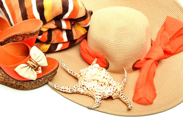Strandhatt, håndkle, stilige kvinnesko og et skjell. – stockfoto
