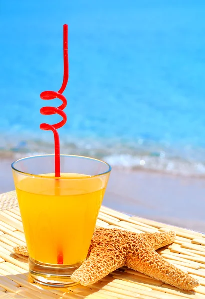 Sjöstjärnor, glas av orange cocktail mot det blå havet — Stockfoto