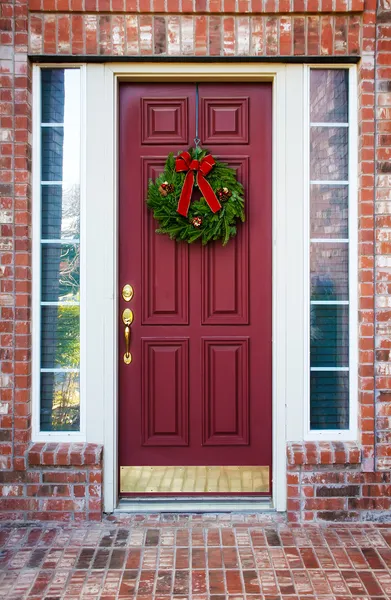 Corona de Navidad en una puerta roja — Foto de Stock