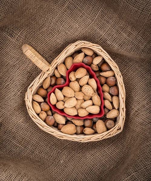 Herzförmiger Korb und Schüssel mit Mandeln und Haselnüssen — Stockfoto