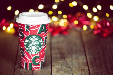 Dallas, Teksas - 4 Kasım 2021 Starbucks popüler bayram içeceği, yeni tasarlanan 2021 yılbaşı bardağında servis edildi. Noel arkaplanına karşı ahşap köy masasında görüntülendi.