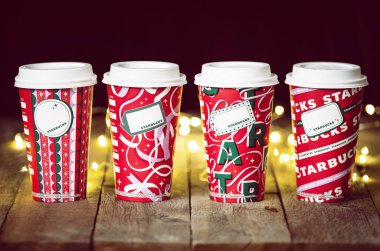 Dallas, Teksas - 5 Kasım 2021: 2021 'de tasarlanmış bir dizi Starbucks kahvesi. Ahşap kırsal masada ve arka planda neşeli Noel telli lambalarda sergilenir..