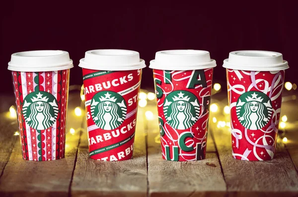 Dallas, Teksas - 5 Kasım 2021: 2021 'de tasarlanmış bir dizi Starbucks kahvesi. Ahşap kırsal masada ve arka planda neşeli Noel telli lambalarda sergilenir..