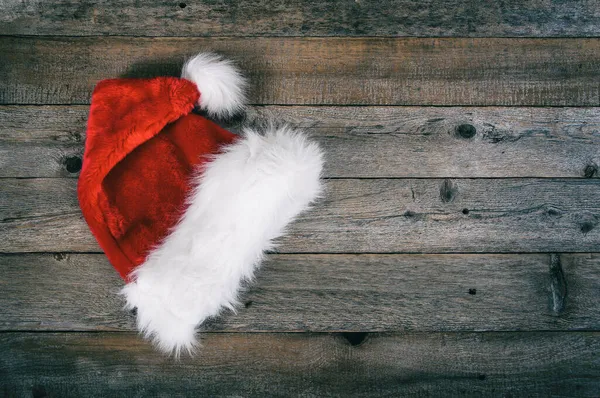 レッドサンタクリスマス帽子は素朴な木製の背景に置かれました — ストック写真