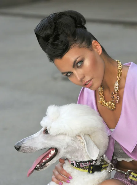 Modelo segurando um cão branco vestindo roupas de grife de alta costura rosa — Fotografia de Stock