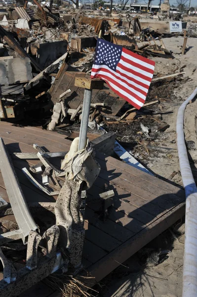 New york, ny - november 09: een Amerikaanse vlag vliegt van het verbrande huis in een beschadigd gebied het luchtig punt deel van far rockaway in de borough queens van New York, 9 november 2012. — Stockfoto