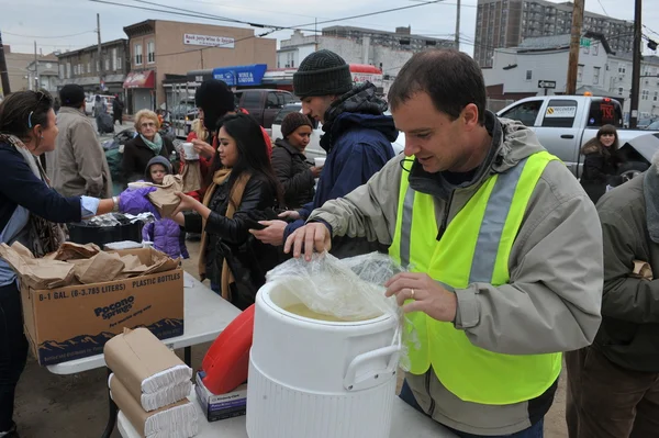 Queens, ny - 11 Kasım: Giysi ve malzemeleri rockaway plaj alanı 11 Kasım 2012 tarihinde kasırga queens, new york, ABD, kumlu gelen darbe sonrası sıcak yemek, ilgili yardım alma. — Stok fotoğraf